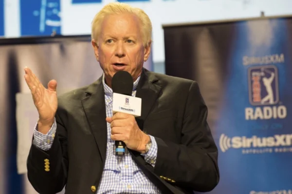 Experienced golf instructor speaking into a microphone during a professional golf media or industry discussion